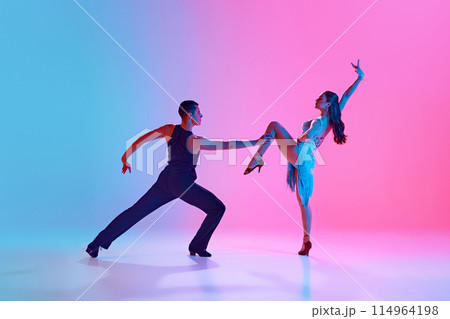 Man and woman, ballroom dancers, performing full of feelings tango dance in neon lighting against gradient background. Man and woman, ballroom dancers, performing full of feelings tango dance in neon lighting against gradient background. 114964198