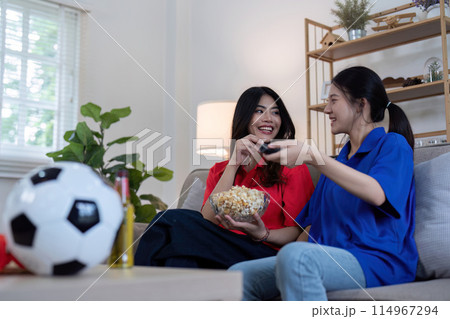Asian lesbian couple watching Euro football match at home. Concept of cheer and football Asian lesbian couple watching Euro football match at home. Concept of cheer and football 114967294