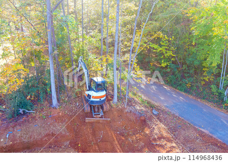 Construction is taking place as tractor uproots trees, clearing land for construction Construction is taking place as tractor uproots trees, clearing land for construction 114968436