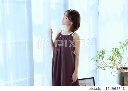 部屋の中でレースカーテン越しにくつろぐ女性 部屋の中でレースカーテン越しにくつろぐ女性 114968848