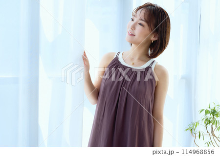 部屋の中でレースカーテン越しにくつろぐ女性 部屋の中でレースカーテン越しにくつろぐ女性 114968856