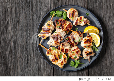 grilled mini pork skewers on a plate, top view 114970548