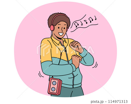 African American man in retro clothes with cassette player on belt listens to music in headphones African American man in retro clothes with cassette player on belt listens to music in headphones 114971313
