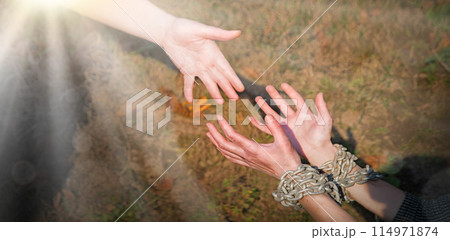 Bound hands reach out to the outstretched hand for help 114971874
