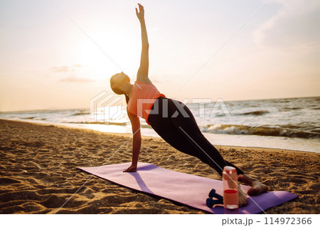 Young woman in sportswear doing yoga, fitness exerciseon the beach. Sport, Active life. 114972366