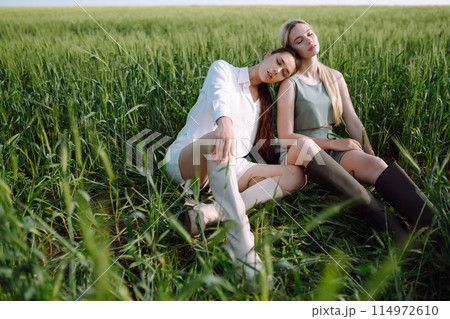 Two Beautiful woman in the green field. Nature, vacation, relax and lifestyle. Summer landscape. Two Beautiful woman in the green field. Nature, vacation, relax and lifestyle. Summer landscape. 114972610