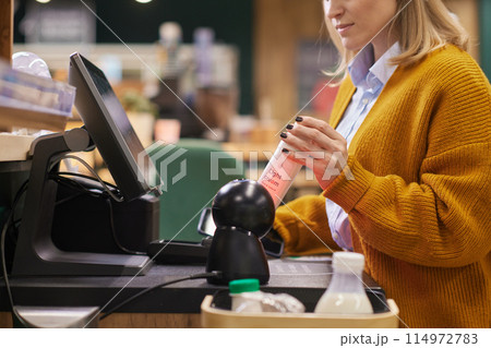 Close up of unrecognizable woman scanning dairy cream bottle while using self checkout in supermarket copy space Close up of unrecognizable woman scanning dairy cream bottle while using self checkout in supermarket copy space 114972783