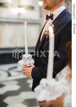 Bride and groom holding candles in church Bride and groom holding candles in church 114973461