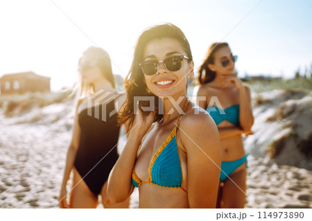 Three attractive women enjoying a holiday on the sea shore. Summer, relax and lifestyle concept. 114973890