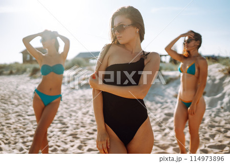 Three beautiful girls on the beach at sunset. Vacation time laughing and smiling. 114973896