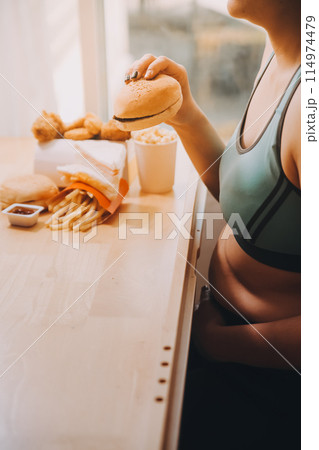 Binge eating disorder concept with woman eating fast food burger, fired chicken , donuts and desserts Binge eating disorder concept with woman eating fast food burger, fired chicken , donuts and desserts 114974479