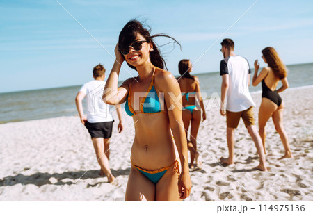 Group of friends having fun and running along beach. Young friends enjoying on beach holiday. Summertime Group of friends having fun and running along beach. Young friends enjoying on beach holiday. Summertime 114975136