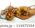 Cutting board with bunch of organic pink grapes on white wooden background.. 114975564
