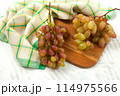 Cutting board with bunch of organic pink grapes on white wooden background.. 114975566