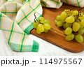 Cutting board with bunch of organic green grapes on white wooden background.. 114975567
