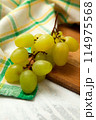 Cutting board with bunch of organic green grapes on white wooden background.. 114975568