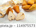 Whole and halves of pears, wicker basket and yellow kitchen towel on white wooden background.. 114975573