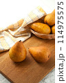 Cutting board with pears, wicker basket and yellow kitchen towel on white wooden background.. 114975575