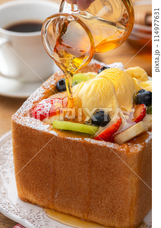 アイスクリームとフルーツをトッピングしたハニートーストに蜂蜜をかける アイスクリームとフルーツをトッピングしたハニートーストに蜂蜜をかける 114977631