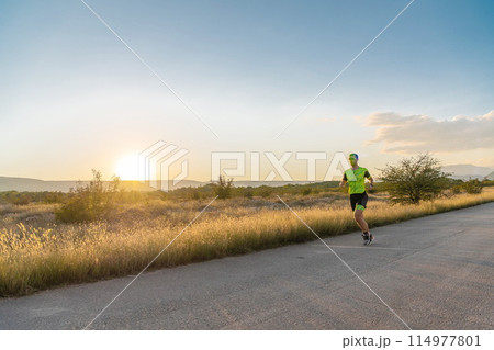 Triathlete in professional gear running early in the morning, preparing for a marathon, dedication to sport and readiness to take on the challenges of a marathon. Triathlete in professional gear running early in the morning, preparing for a marathon, dedication to sport and readiness to take on the challenges of a marathon. 114977801