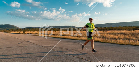 Triathlete in professional gear running early in the morning, preparing for a marathon, dedication to sport and readiness to take on the challenges of a marathon.  114977806