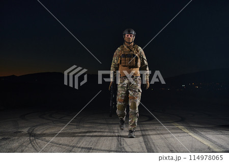 A professional soldier in full military gear striding through the dark night as he embarks on a perilous military mission A professional soldier in full military gear striding through the dark night as he embarks on a perilous military mission 114978065