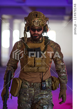 A professional soldier undertakes a perilous mission in an abandoned building illuminated by neon blue and purple lights A professional soldier undertakes a perilous mission in an abandoned building illuminated by neon blue and purple lights 114978148