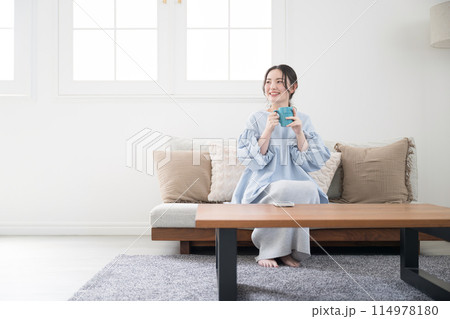 コーヒーや飲み物を持ってリビングでくつろぐ女性 114978180