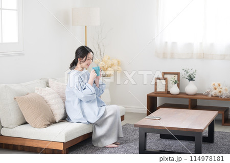 コーヒーや飲み物を持ってリビングでくつろぐ女性 コーヒーや飲み物を持ってリビングでくつろぐ女性 114978181