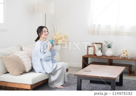 コーヒーや飲み物を持ってリビングでくつろぐ女性 コーヒーや飲み物を持ってリビングでくつろぐ女性 114978182