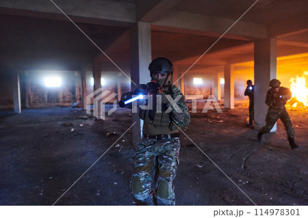 A group of professional soldiers bravely executes a dangerous rescue mission, surrounded by fire in a perilous building. 114978301