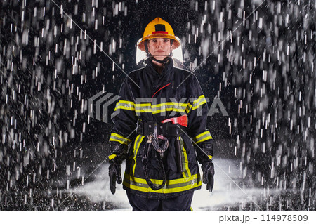 A determined female firefighter in a professional uniform striding through the dangerous, rainy night on a daring rescue mission, showcasing her unwavering bravery and commitment to saving lives. 114978509