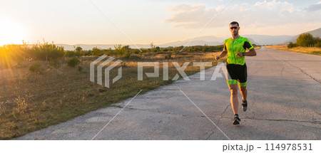 Triathlete in professional gear running early in the morning, preparing for a marathon, dedication to sport and readiness to take on the challenges of a marathon.  114978531
