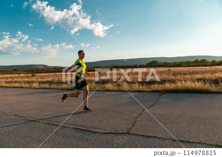 Triathlete in professional gear running early in the morning, preparing for a marathon, dedication to sport and readiness to take on the challenges of a marathon. Triathlete in professional gear running early in the morning, preparing for a marathon, dedication to sport and readiness to take on the challenges of a marathon. 114978815
