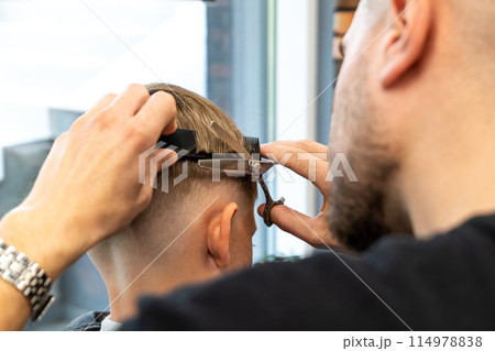 Hairdresser's hands making hairstyle to little boy, close up Hairdresser's hands making hairstyle to little boy, close up 114978838
