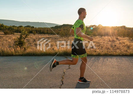 Triathlete in professional gear running early in the morning, preparing for a marathon, dedication to sport and readiness to take on the challenges of a marathon. Triathlete in professional gear running early in the morning, preparing for a marathon, dedication to sport and readiness to take on the challenges of a marathon. 114978873