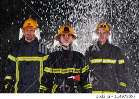 A group of professional firefighters marching through the rainy night on a rescue mission, their determined strides and fearless expressions reflecting their unwavering bravery and unwavering 114979057