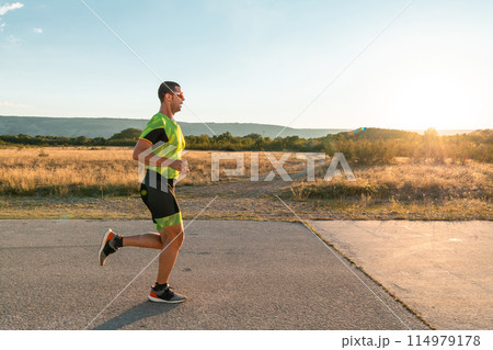 Triathlete in professional gear running early in the morning, preparing for a marathon, dedication to sport and readiness to take on the challenges of a marathon.  114979178