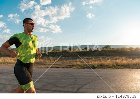 Triathlete in professional gear running early in the morning, preparing for a marathon, dedication to sport and readiness to take on the challenges of a marathon.  114979319