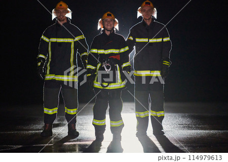 A group of professional firefighters marching through night on a rescue mission, their determined strides and fearless expressions reflecting their unwavering bravery and unwavering commitment to A group of professional firefighters marching through night on a rescue mission, their determined strides and fearless expressions reflecting their unwavering bravery and unwavering commitment to 114979613
