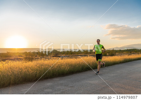 Triathlete in professional gear running early in the morning, preparing for a marathon, dedication to sport and readiness to take on the challenges of a marathon.  114979807