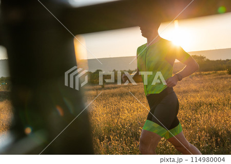 Triathlete in professional gear running early in the morning, preparing for a marathon, dedication to sport and readiness to take on the challenges of a marathon.  114980004