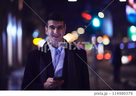 Smiling Meedle Eastern man walking down street near modern office building, 114980379