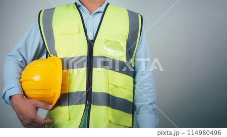 Civil engineer architect standing holding a safety helmet on grey background, Construction site plans to build high-rise buildings, Engineer building concept, Background for construction. 114980496