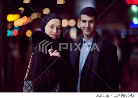 Happy multicultural business couple walking together outdoors in an urban city street at night near a jewelry shopping store window. 114980542