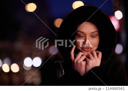 Muslim woman walking on an urban city street on a cold winter night wearing hijab Muslim woman walking on an urban city street on a cold winter night wearing hijab 114980561