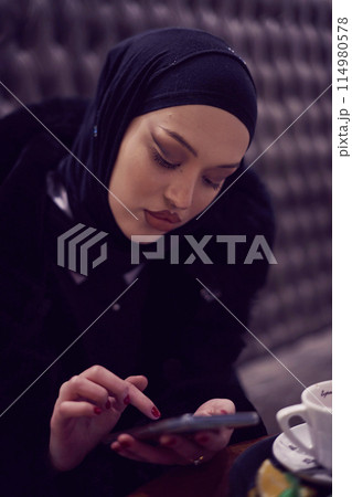 Muslim woman walking on an urban city street on a cold winter night wearing hijab 114980578