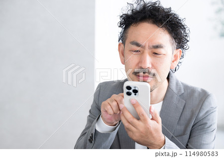 スマホを見ながら老眼が始まって困る男性 スマホを見ながら老眼が始まって困る男性 114980583