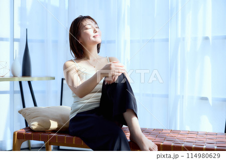 部屋の中で椅子に座って朝日を浴びる女性 部屋の中で椅子に座って朝日を浴びる女性 114980629