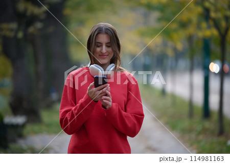 Sporty woman checks smartphone before doing some exercises listens music from a playlist 114981163
